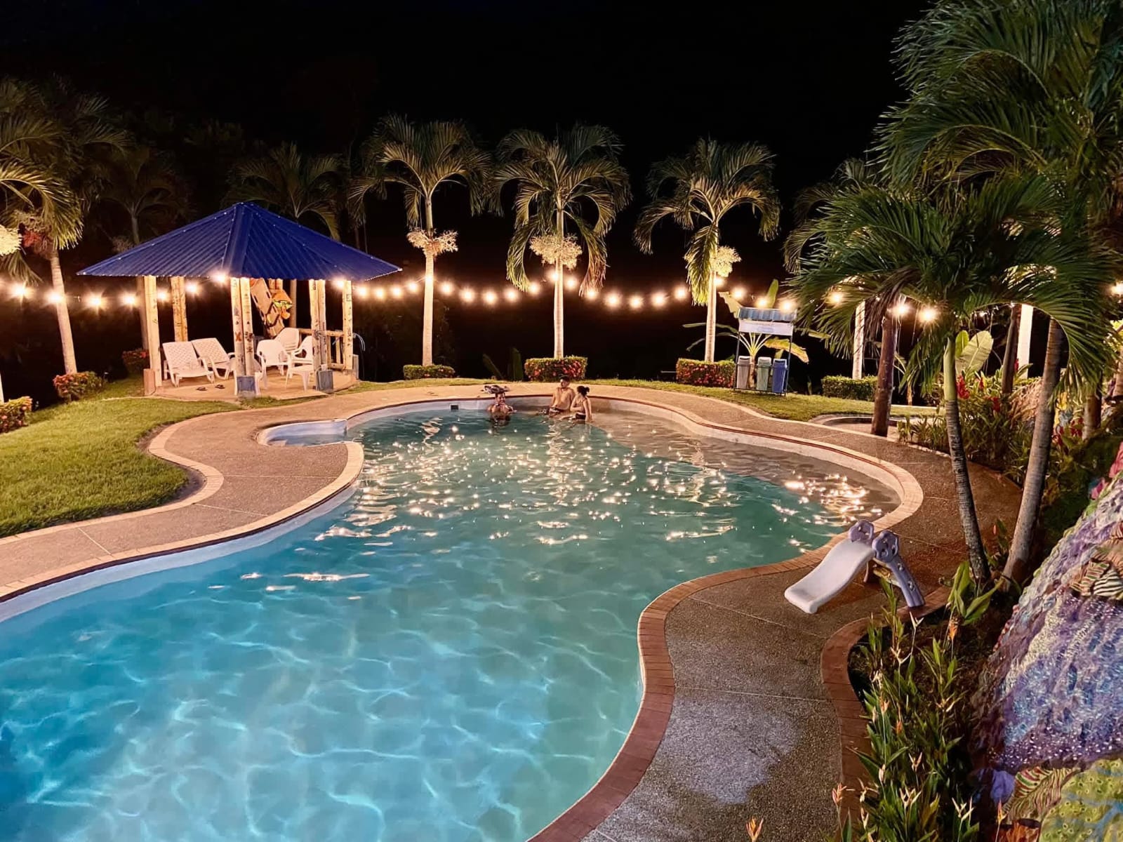 Zona de piscina iluminada durante la noche en el ecohotel